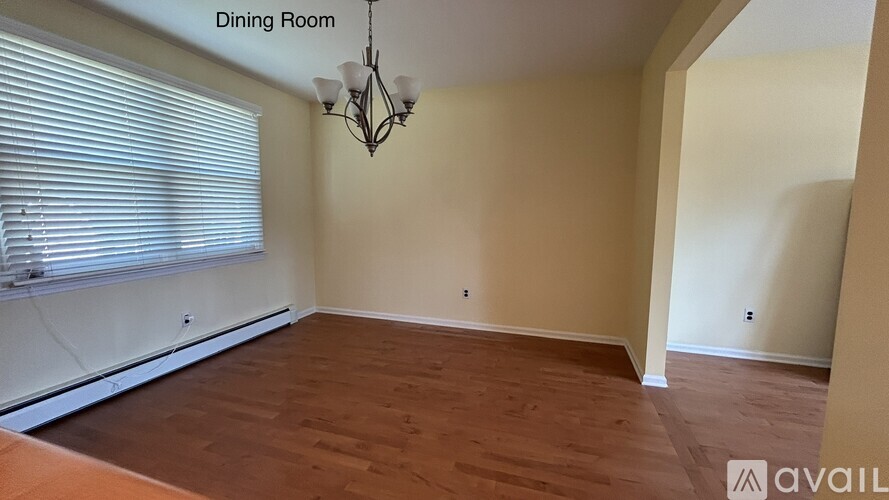 A dining room with wooden floors and a chandelier.