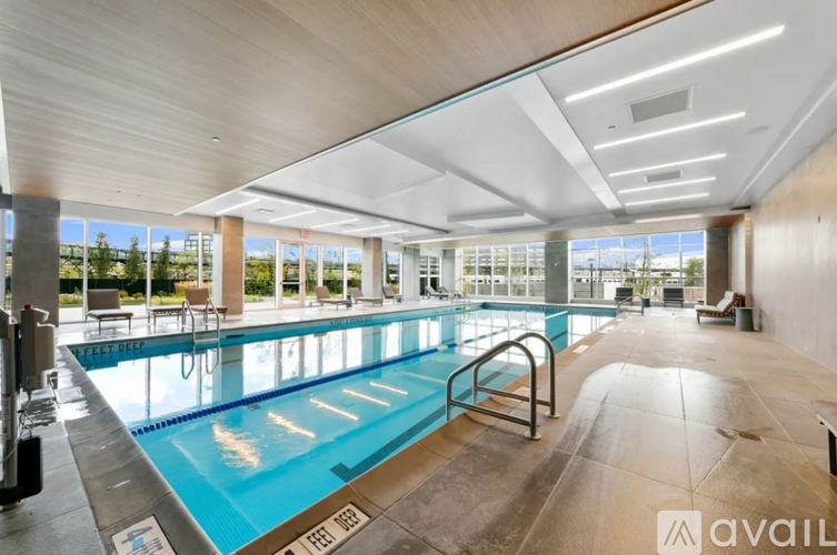 A large indoor swimming pool with a glass ceiling and a diving board.