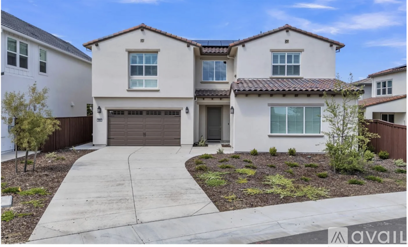 A white house with a brown garage door is for sale.
