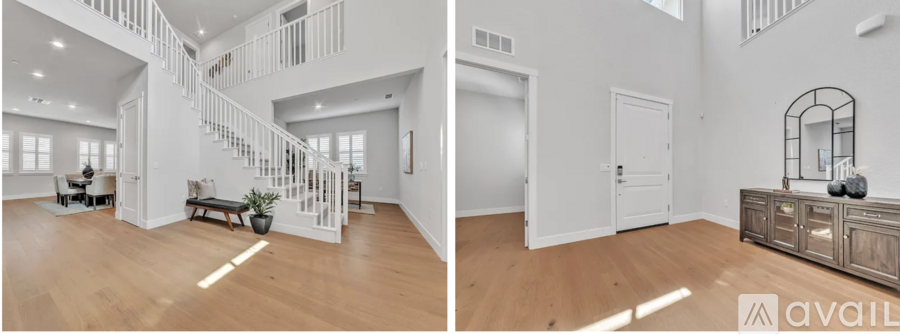 A spacious living room with a staircase and a side table with a mirror.