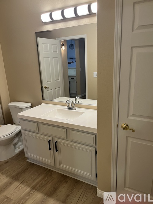 A bathroom with a toilet, sink and mirror.