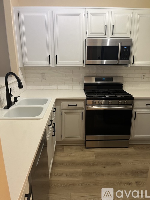 A kitchen with white cabinets and a black stove top oven.