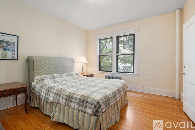 A bedroom with a bed, nightstand, and window.