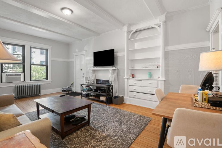 A living room with a television, a coffee table, and a rug.