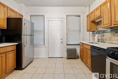 A kitchen with wooden cabinets and a black fridge.