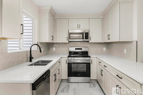 A kitchen with white cabinets and a marble countertop.