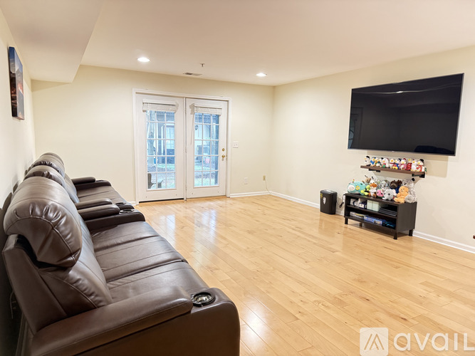 A living room with a brown leather couch and a flat screen TV mounted on the wall.
