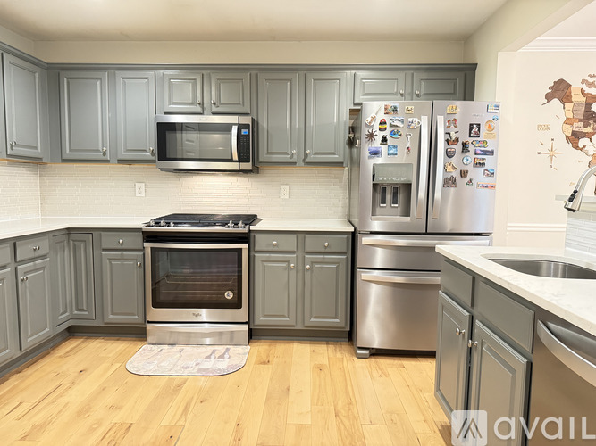 A kitchen with wooden floors and a refrigerator covered in magnets.
