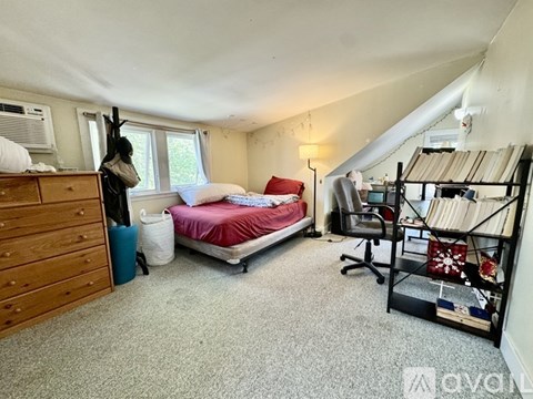 A bedroom with a bed, desk, and chair.