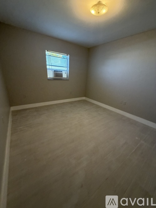 A room with a window and wooden flooring.