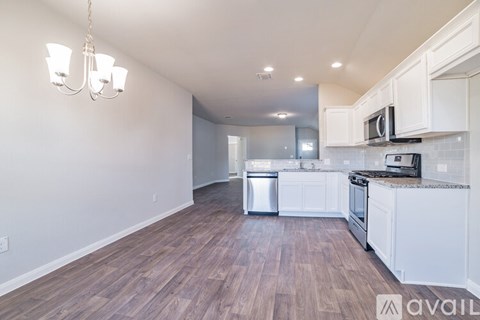 A kitchen with white cabinets and a wooden floor.