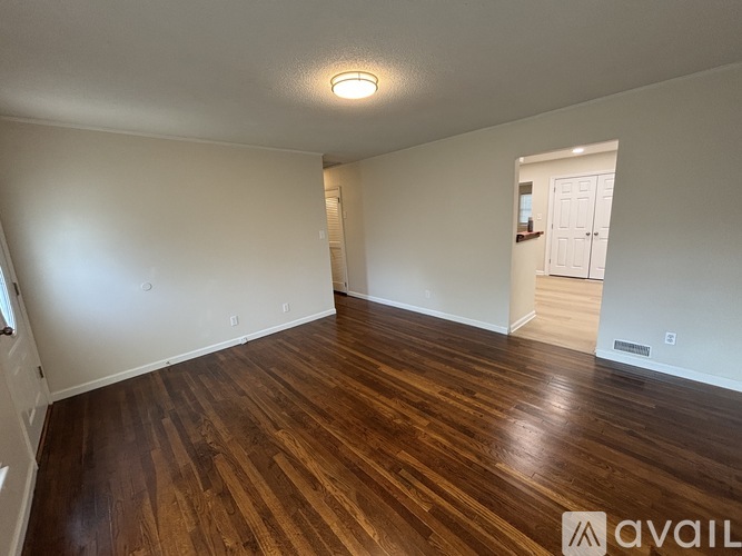 A room with wooden flooring and white walls.
