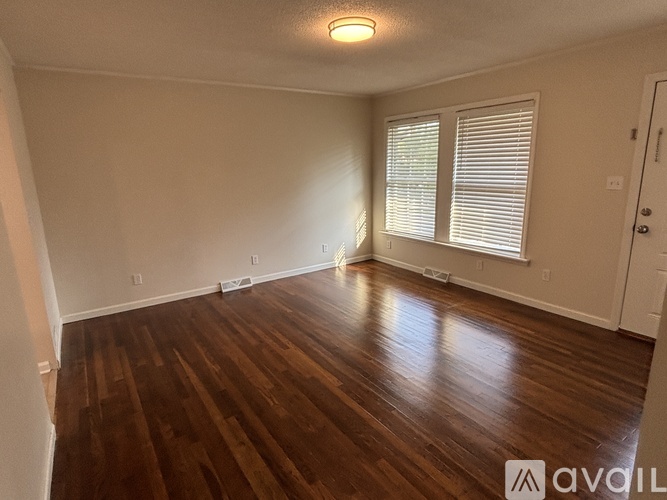 A room with wooden flooring and a window with blinds.