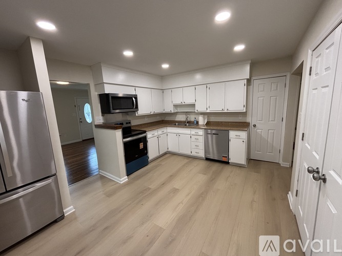 A kitchen with white cabinets and a wooden floor.