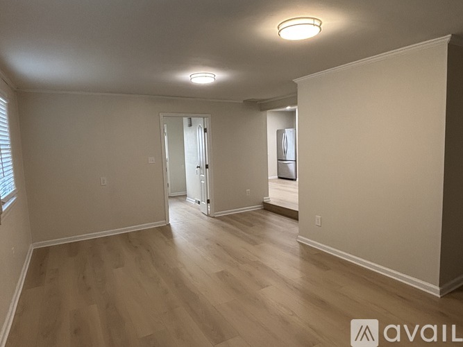 A spacious room with wooden flooring and a white door in the background.