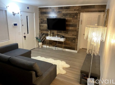 A living room with a dark grey couch and a wooden wall.