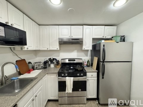 A kitchen with white cabinets and a stainless steel refrigerator.