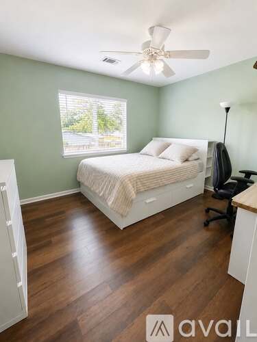 A bedroom with a bed, desk, and chair.