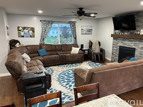 A living room with a brown leather couch and a fireplace.