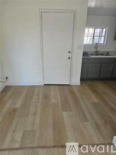 A room with a white door and wooden flooring.