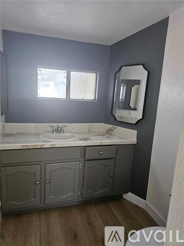 A bathroom with a sink, mirror, and cabinets.