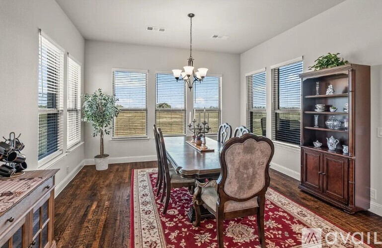 A dining room with a table set for two and a view of the backyard.