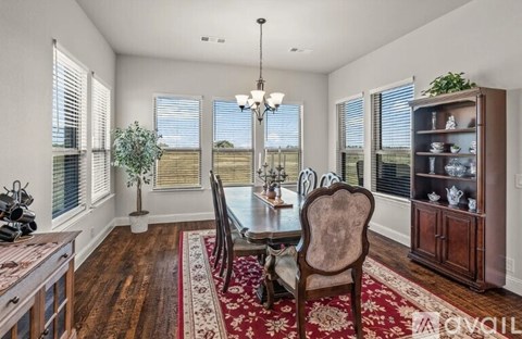 A dining room with a table set for two and a view of the backyard.