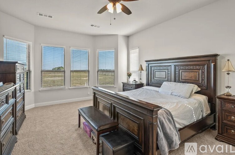 A bedroom with a large bed, a dresser, and a ceiling fan.