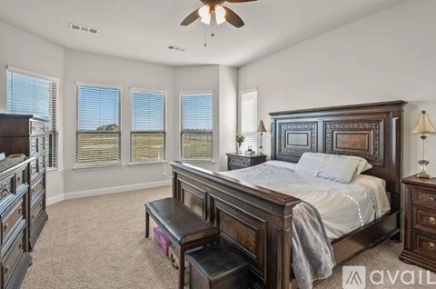 A bedroom with a large bed, a dresser, and a ceiling fan.