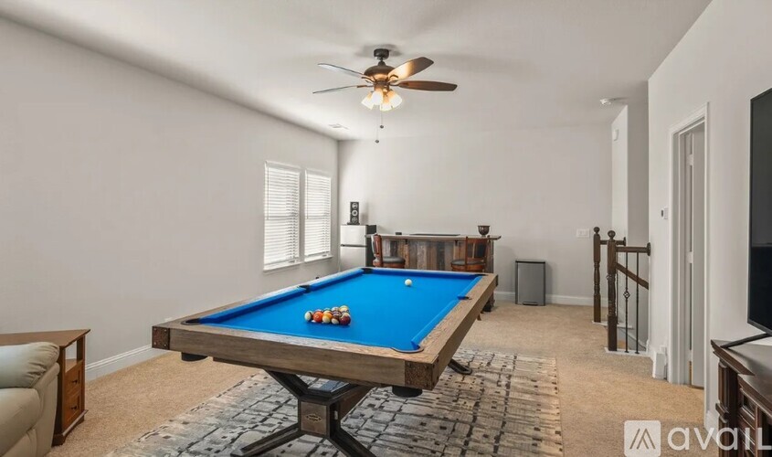 A pool table with a blue cloth and several balls is in the center of the room.