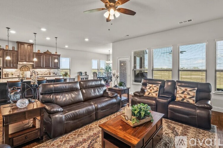 A living room with brown leather furniture and a ceiling fan.