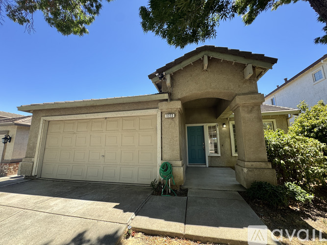A house with a white garage door and a green hose on the sidewalk.