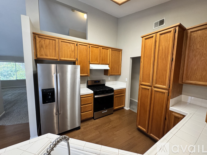 A kitchen with wooden cabinets and a stainless steel refrigerator.