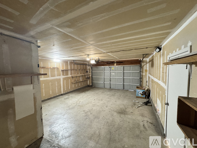 A spacious unfinished room with a concrete floor and walls covered in drywall.