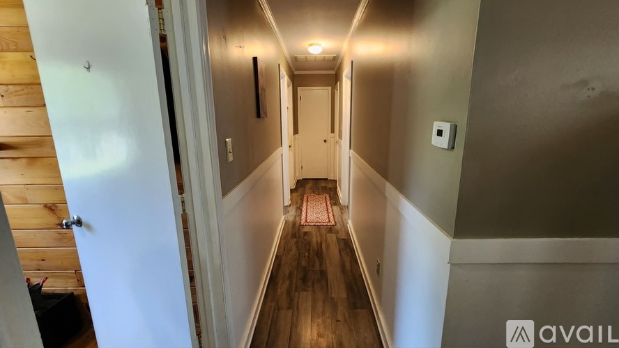 A hallway with wooden floors and white walls.