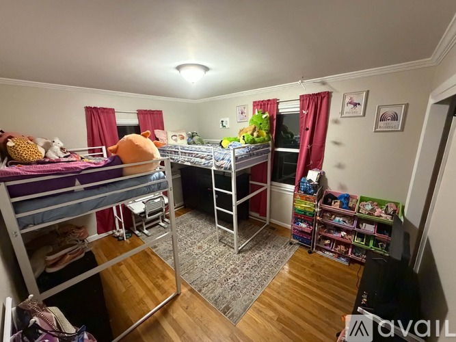 A bedroom with two bunk beds and a single bed with a red curtain.