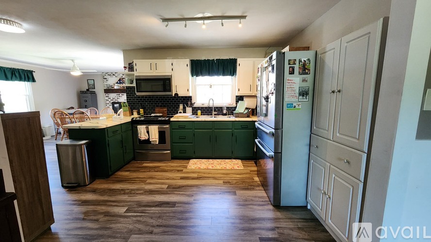A kitchen with green cabinets and a wooden floor.