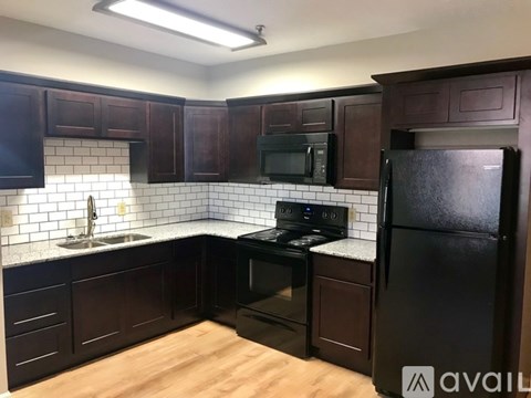 A kitchen with dark wood cabinets and black appliances.