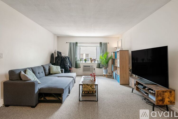 A living room with a grey sofa and a black television.