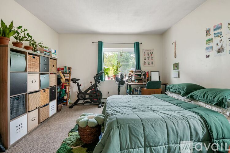 A bedroom with a green bed and a bicycle in the corner.