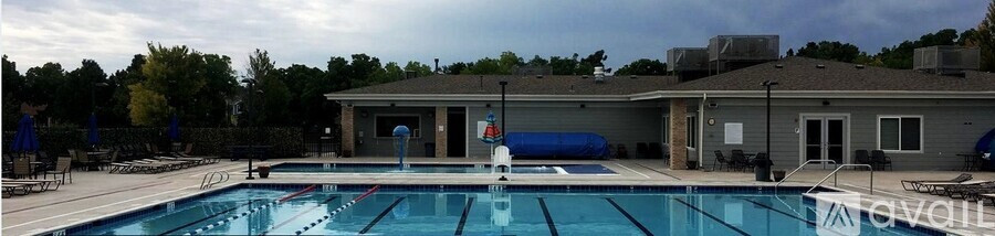 A large swimming pool with a diving board and a building in the background.