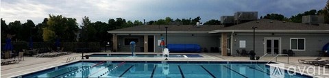 A large swimming pool with a diving board and a building in the background.