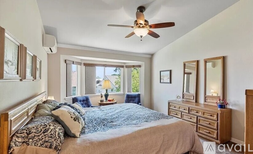 A bedroom with a bed, dresser, mirror, and window.