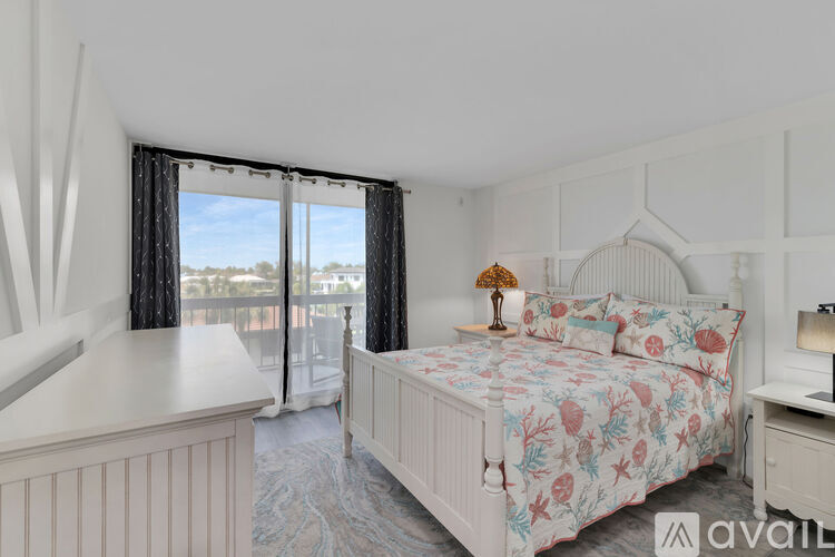 A bedroom with a large bed and a balcony with a view of the outside.