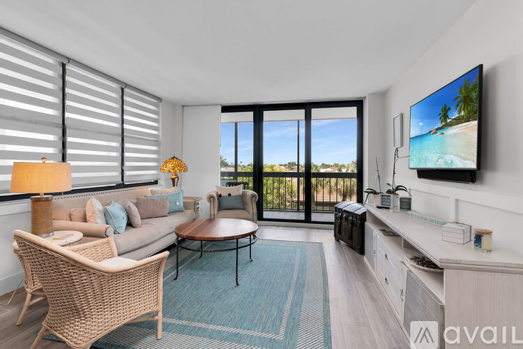 A living room with a couch, chair, and television displaying a beach scene.