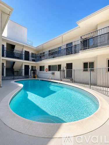 A small pool in a courtyard surrounded by a white building.