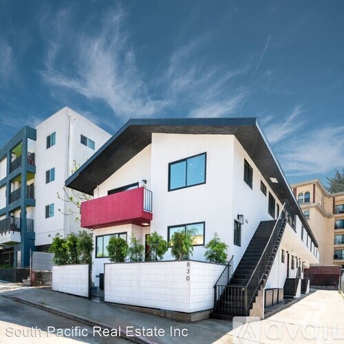 A modern white building with a red awning is for sale.