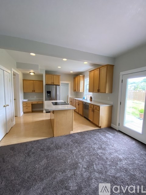 A kitchen with wooden cabinets and a grey carpet.