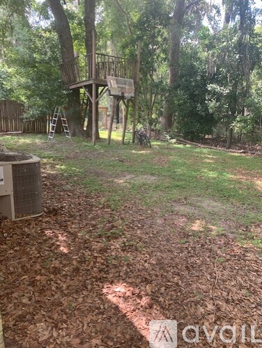 A treehouse in a backyard surrounded by trees.