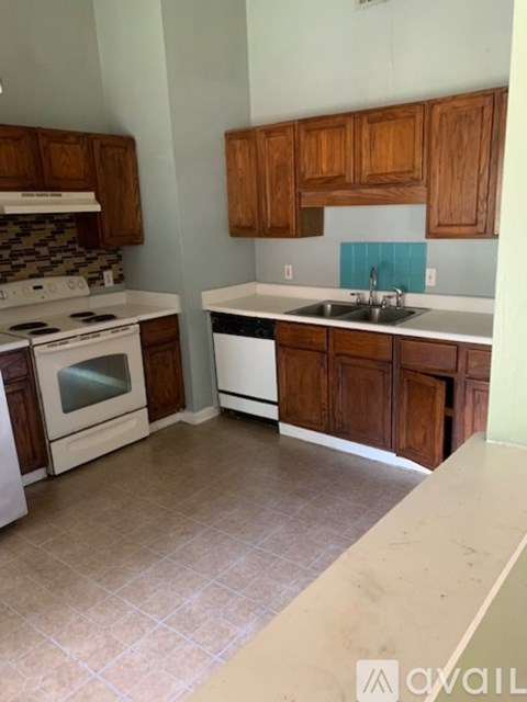 A kitchen with a white stove top oven and a white dishwasher.